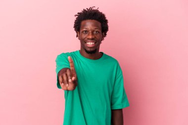 Pembe arka planda izole edilmiş genç Afro-Amerikan bir numara parmağıyla görünüyor..