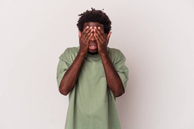 Genç Afrikalı Amerikalı, beyaz arka planda izole edilmiş. Gözleri elleriyle kapatmaktan korkuyor..