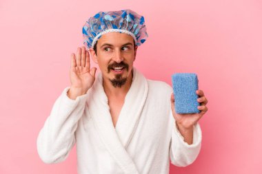 Beyaz bir genç, elinde süngerle duşa giriyor. Pembe arka planda, bir dedikoduyu dinlemeye çalışıyor..