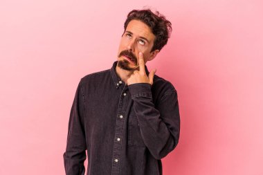 Kafkasyalı genç bir adam pembe arka planda izole edilmiş ağlıyordu, bir şeyden mutsuzdu, acı ve kafa karışıklığı içeriyordu..