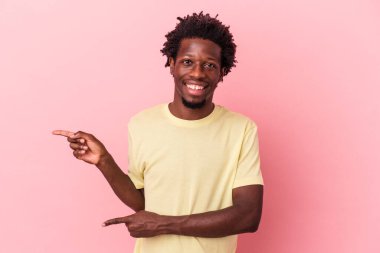 Pembe arka planda izole edilmiş genç Afro-Amerikalı adam işaret parmağıyla işaret ederek heyecanlanıyor..