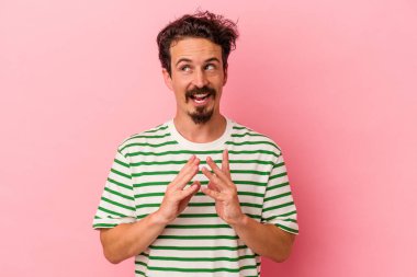 Kafkasyalı genç bir adam pembe arka planda izole edilmiş bir plan yapıyor, bir fikir kuruyor..