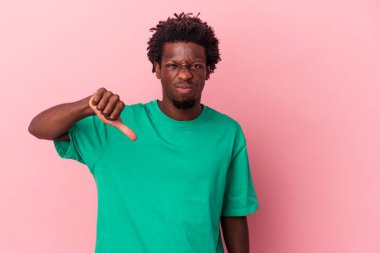 Pembe arka planda izole edilmiş genç Afro-Amerikan adam baş parmağını aşağı gösteriyor, hayal kırıklığı konsepti.
