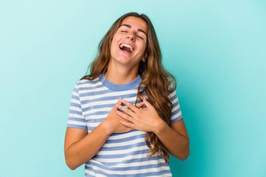 Mavi arka planda izole edilmiş beyaz bir kadın, dost canlısı bir ifadeye sahip, avuçlarını göğsüne bastırıyor. Aşk konsepti.