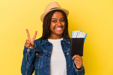 Sarı arka planda pasaportu olan genç Afrikalı Amerikalı kadın iki numarayı parmaklarıyla gösteriyor..