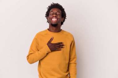 Beyaz arka planda izole edilmiş genç Afrikalı Amerikalı adam elini göğsüne koyduğunda kahkahalar atıyor..