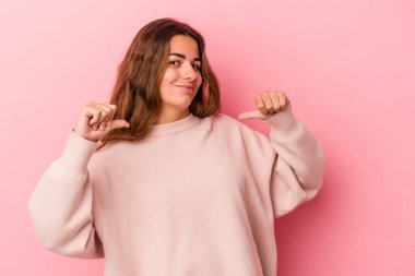 Pembe arka planda izole genç beyaz kadın gururlu ve kendinden emin hissediyor, örnek olarak..