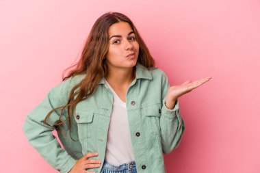 Pembe arka planda izole edilmiş genç beyaz kadın bir avuç içinde fotokopi alanı ve belinde bir el daha gösteriyor..