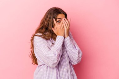 Pembe arka planda izole edilmiş genç beyaz kadın parmaklarıyla gözünü kırp korkmuş ve gergin..