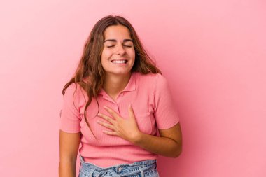 Pembe arka planda soyutlanmış beyaz bir kadın yüksek sesle gülüyor ve elini göğsüne koyuyor..