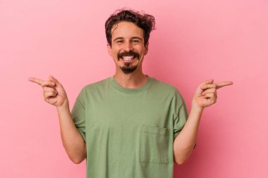 Pembe arka planda izole edilmiş genç beyaz adam farklı fotokopi alanlarını gösteriyor, birini seçiyor, parmaklarıyla gösteriyor..