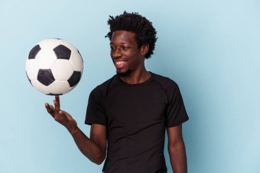 Genç Afro-Amerikan futbol oynayan adam mavi arka planda izole edilmiş.