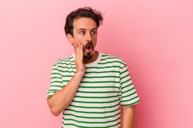 Pembe arka planda izole edilmiş genç beyaz adam gördüğü bir şey yüzünden şoka uğruyor..