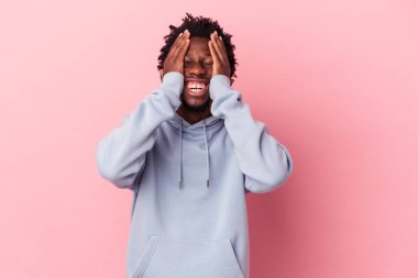 Pembe arka planda izole edilmiş genç Afro-Amerikalı adam mutlu bir şekilde ellerini başının üstünde tutarak gülüyor. Mutluluk kavramı.