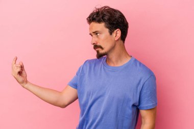 Pembe arka planda izole edilmiş genç beyaz adam sanki seni davet ediyormuş gibi seni işaret ediyor..
