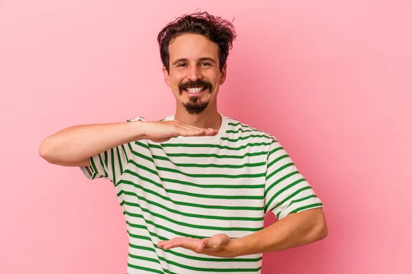 Junge Kaukasische Mann Isoliert Auf Rosa Hintergrund Hält Etwas Mit — Stockfoto