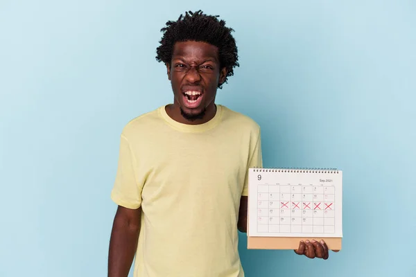 Jonge Afrikaanse Amerikaanse Man Houden Kalender Geïsoleerd Blauwe Achtergrond Schreeuwen — Stockfoto