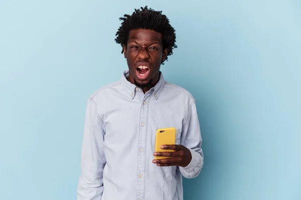 年轻的非洲裔美国人手持蓝色背景的手机 怒吼不已 咄咄逼人 — 图库照片