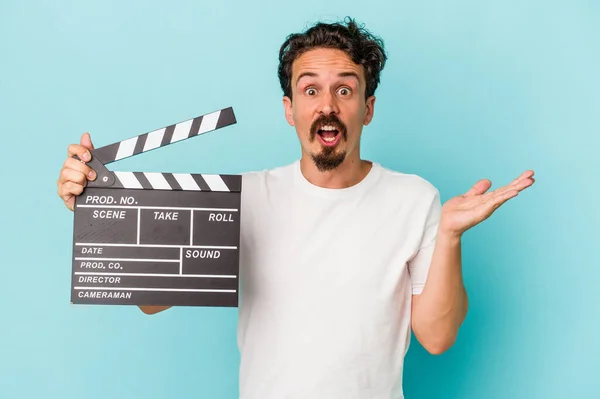 Young Caucasian Man Holding Clapperboard Isolated Blue Background Surprised Shocked — Stock Photo, Image