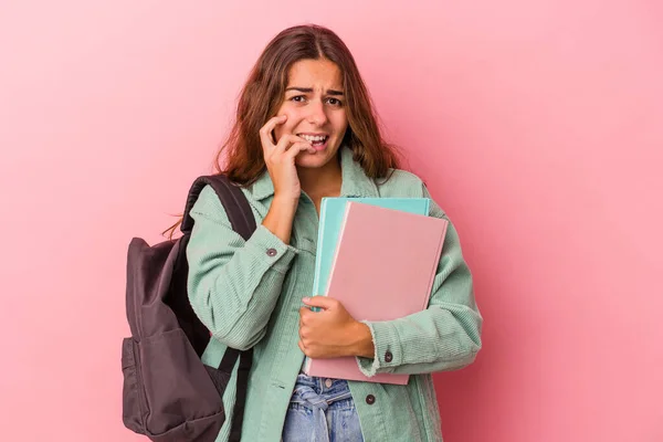 年轻的高加索女学生拿着用粉色背景的书 咬着指甲 紧张而焦虑 — 图库照片