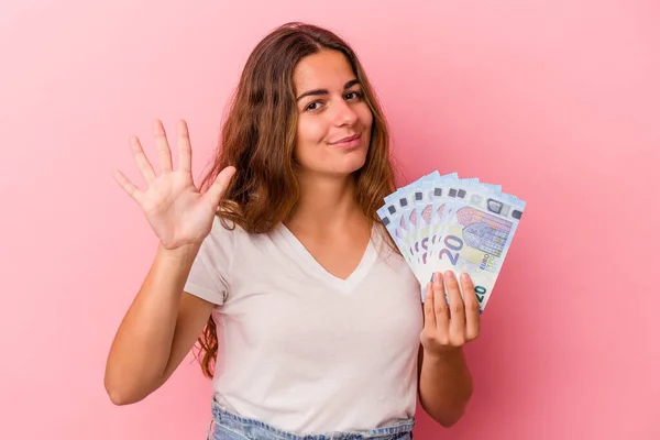 Mladá Běloška Drží Bankovky Izolované Růžovém Pozadí Veselým Úsměvem Ukazující — Stock fotografie