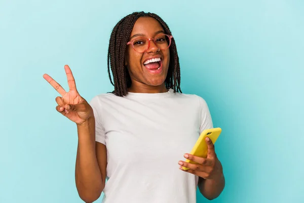 Ung Afrikansk Amerikansk Kvinna Håller Mobiltelefon Isolerad Blå Bakgrund Glad — Stockfoto