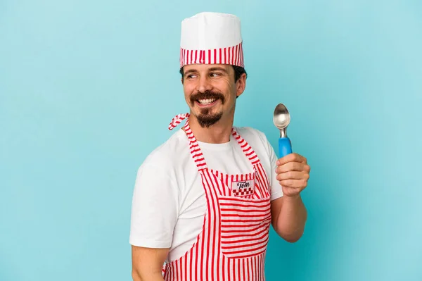 Young Caucasian Maker Holding Scoop Isolated Blue Background Looks Aside — Stock Photo, Image