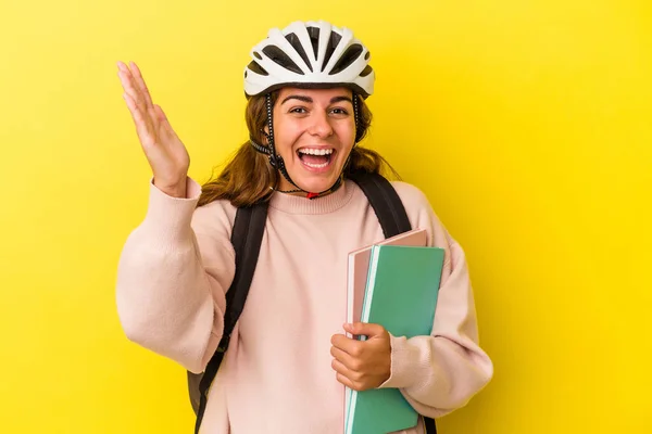 若いです白人学生女性を身に着けています自転車ヘルメット黄色の背景に隔離されました楽しい驚きを受け取ります 興奮し 手を上げます — ストック写真