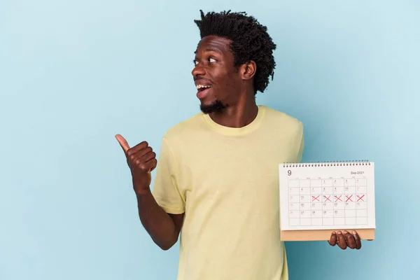 Jonge Afro Amerikaanse Man Houdt Kalender Geïsoleerd Blauwe Achtergrond Punten — Stockfoto