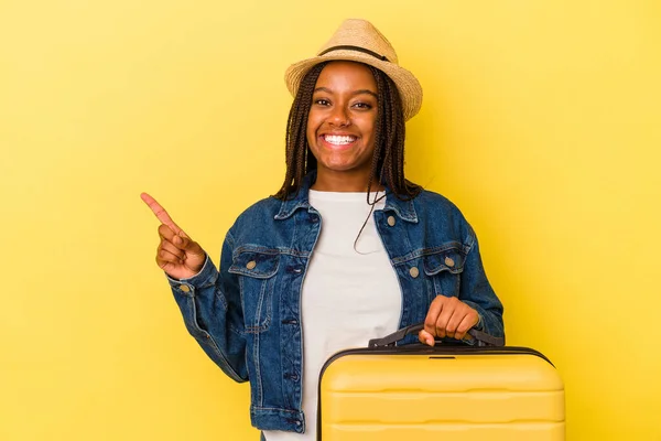 Молода Афроамериканська Мандрівниця Тримає Валізу Ізольованою Жовтому Фоні Посміхається Вказує — стокове фото