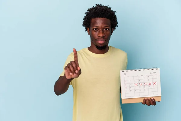 Mladý Africký Američan Drží Kalendář Izolované Modrém Pozadí Ukazující Číslo — Stock fotografie