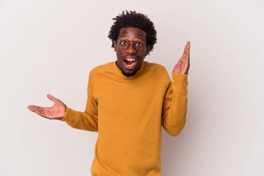 Beyaz arka planda izole edilmiş genç Afro-Amerikalı bir adam avuç içinde fotokopi alanı tutuyor, el üstünde tutuyor. Şaşırmış ve mutlu..