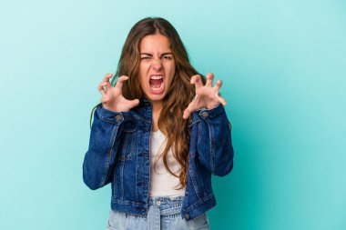 Mavi arka planda izole edilmiş genç beyaz kadın pençelerini kedi taklidi yaparken gösteriyor, agresif bir hareket..