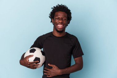 Genç Afro-Amerikan futbol oynayan adam mavi arka planda izole edilmiş gülüyor ve eğleniyor..