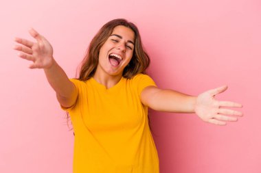 Pembe arka planda izole edilmiş genç beyaz kadın kameraya sarıldığı için kendinden emin..