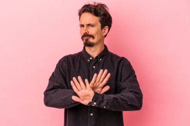 Pembe arka planda izole edilmiş genç beyaz adam inkar jesti yapıyor.