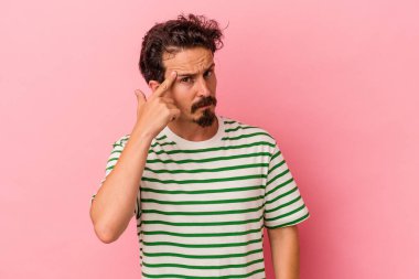 Pembe arka planda izole edilmiş genç beyaz bir adam parmağıyla tapınağı işaret ediyor, düşünüyor ve bir göreve odaklanıyor..