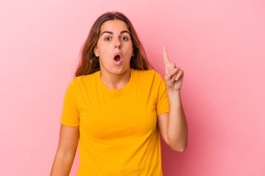 Pembe arka planda izole edilmiş beyaz bir kadın ağzı açık bir şekilde üst tarafı işaret ediyor..