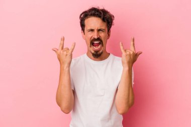 Pembe arka planda izole edilmiş genç beyaz adam boynuzlarını devrim konsepti olarak gösteriyor..