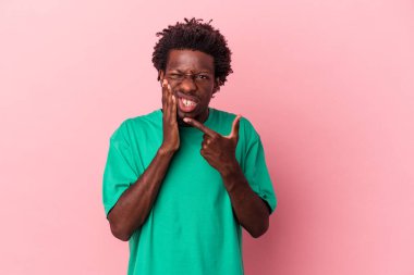Genç Afrikalı Amerikalı bir adam pembe arka planda izole edilmiş güçlü bir diş ağrısı ve azı dişi ağrısı var..