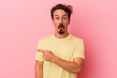 Pembe arka planda izole edilmiş genç beyaz adam yan tarafı gösteriyor.
