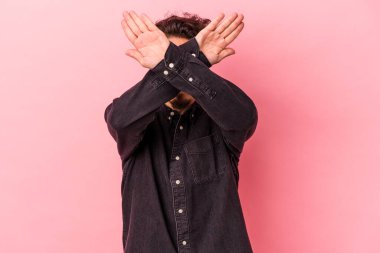 Pembe arka planda izole genç beyaz adam iki kolu çapraz tutuyor, inkar kavramı.