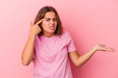 Pembe arka planda izole edilmiş beyaz bir kadın elinde bir ürün tutuyor..