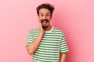 Pembe arka planda izole edilmiş genç beyaz adam yüksek sesle bağırıyor, gözleri açık ve elleri gergin tutuyor..