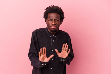 Genç Afro-Amerikalı bir adam pembe arka planda izole edilmiş, tiksinti belirtisi gösteren birini reddediyor..
