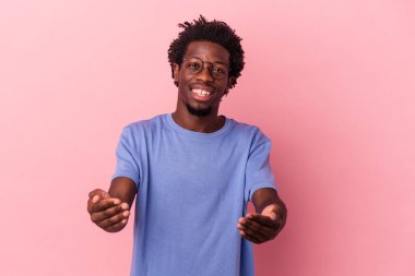 Genç Afrikalı Amerikalı bir adam pembe arka planda izole edilmiş hoş bir ifade sergiliyor..