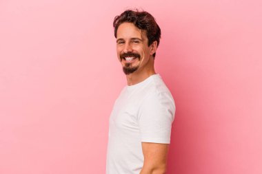 Pembe arka planda izole edilmiş beyaz bir adam. Kendine güveniyor. Kalçaları tutuyor..