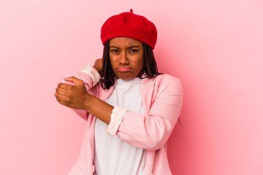 Pembe arka planda izole edilmiş genç Afro-Amerikalı kadın stresten dolayı boynu ağrıyor, masaj yapıyor ve elle dokunuyor..