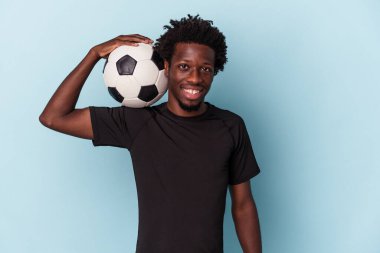Genç Afro-Amerikan futbol oynayan adam mavi arka planda izole edilmiş.