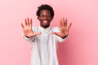 Pembe arka planda izole edilmiş genç Afro-Amerikalı adam on numarayı elleriyle gösteriyor..